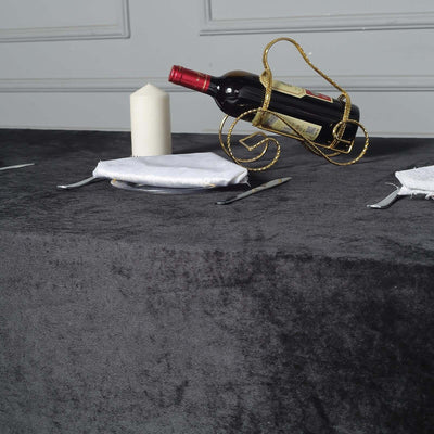 Elegant black tablecloth with wine bottle and candle on a stylish dining setup.