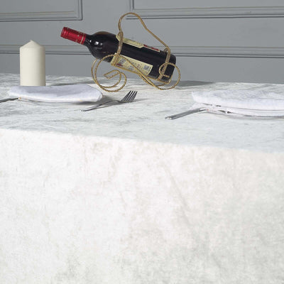 Table set with wine bottle, candle, and napkins on textured white tablecloth.