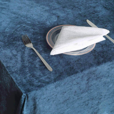 Elegant table setting with a fork, plate, and folded napkin on a blue velvet tablecloth.