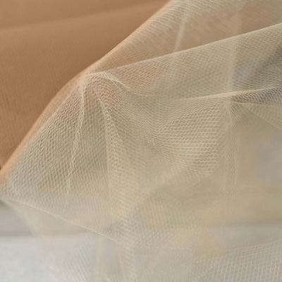 Sheer beige tulle fabric draping elegantly in soft folds.
