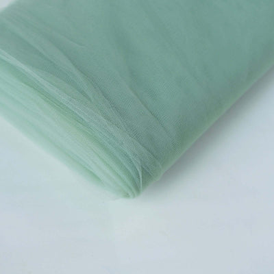 Light green tulle fabric rolled up on a plain backdrop.