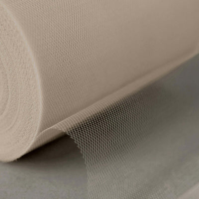 Beige tulle fabric roll on a smooth surface.