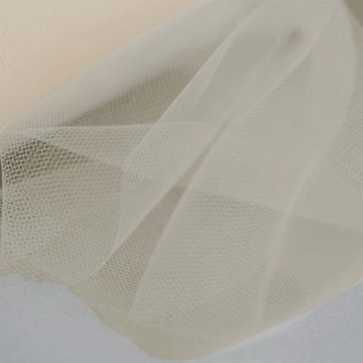Sheer beige tulle fabric draped elegantly on a soft surface.