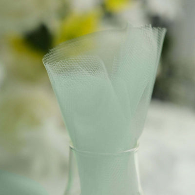 Mint green tulle fabric rolls in a clear vase.