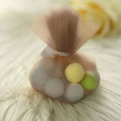Colorful decorative balls in a mesh bag on a soft surface.
