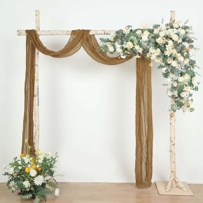 Wooden wedding arch with floral arrangement and draped fabric.