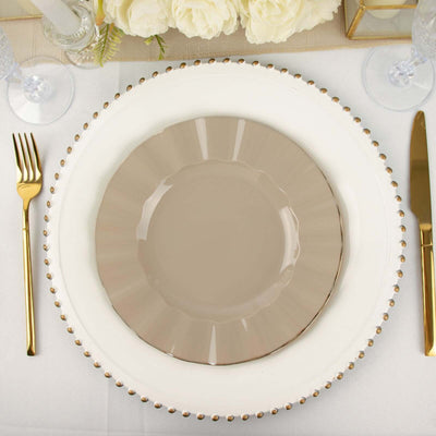 Elegant beige dinner plate on decorative charger in a refined table setting.