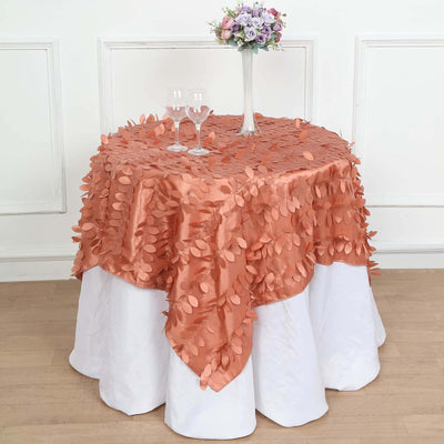 Peach leaf-patterned tablecloth draping over a round table with glasses and flowers.
