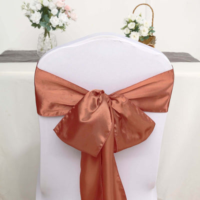 Copper satin chair sash tied in a bow on a white chair.