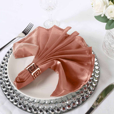 Elegant rose gold napkin with decorative holder on a stylish dinner plate.