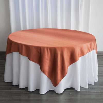 Round table with a rust-colored tablecloth draped over a white table skirt.