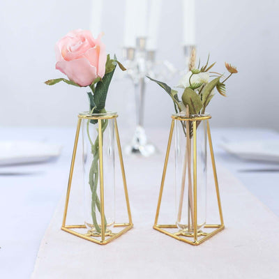 Gold geometric vase holders with pink and white flowers.