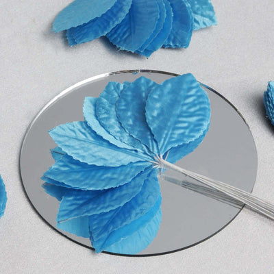 Blue satin flower leaves on a mirror surface.