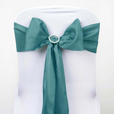 Teal chair sash with pearl detail tied in a bow on a white chair