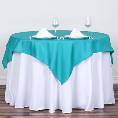 Teal tablecloth draped over a round table set with plates and glasses.