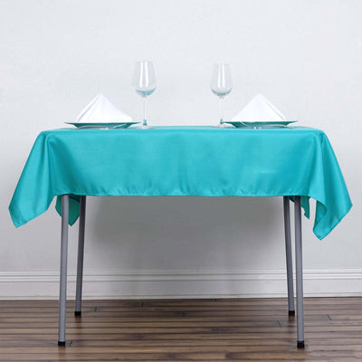Turquoise tablecloth set with plates and glasses on a simple table