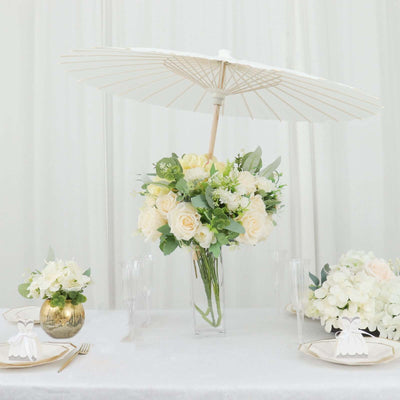 Elegant floral centerpiece with white roses and parasol on a table setting.
