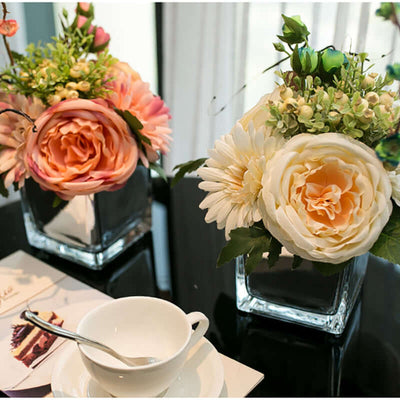 Artificial flower arrangements in glass vases on a table.