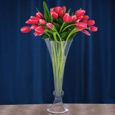 Clear vase filled with pink tulips against a dark blue background.