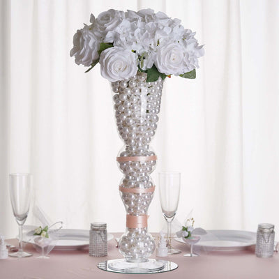 Elegant floral arrangement in a decorative vase filled with pearls.