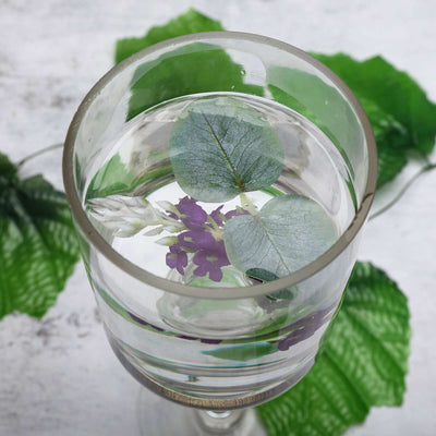 Glass filled with water and floating leaves and flowers.