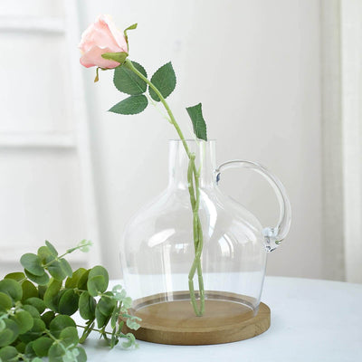 Clear glass vase with pink rose and green leaves