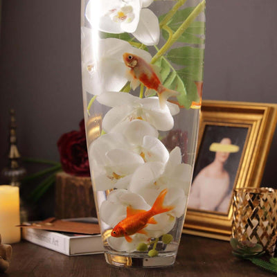 Goldfish in a vase with white orchids on a decorative table