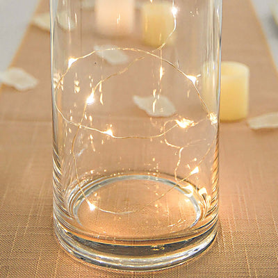 String lights in a glass vase with soft candlelight in the background.