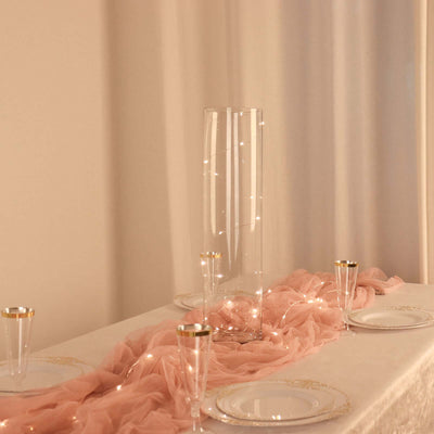 Elegant glass vase with fairy lights on a table with pink runner and decorative plates.