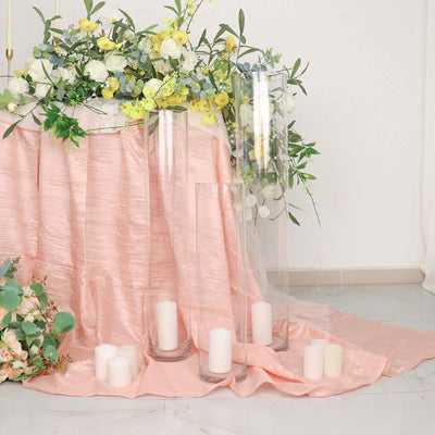 Floral arrangement with candles on a pink tablecloth in a decorated setting.