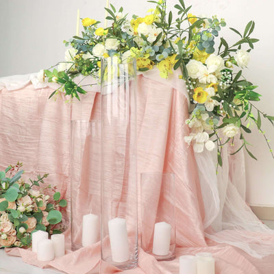 Floral arrangement with candles and draped fabric in soft pastel colors.