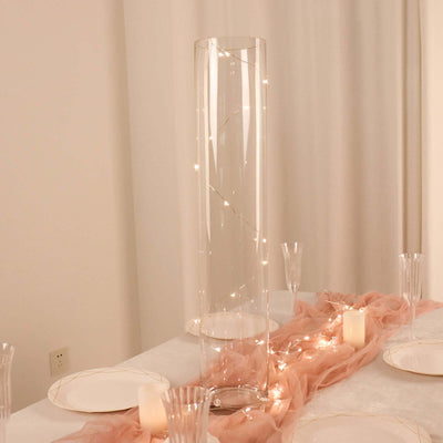 Clear glass vase with fairy lights, elegantly styled on a table setting.