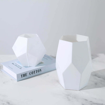 Geometric white vases on a marble surface with a book.