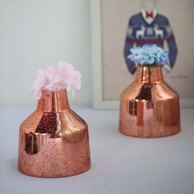 Copper vases with pink and blue flowers on a table.