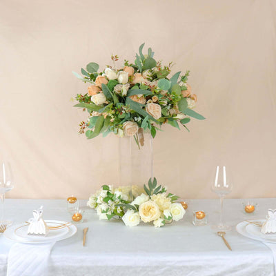 Elegant floral centerpiece arrangement with roses and greenery on a table setting.