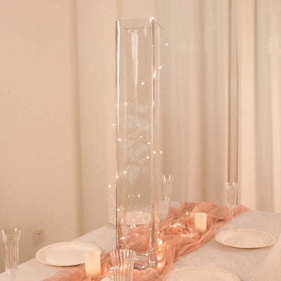 Elegant glass vase with fairy lights on a table setting.
