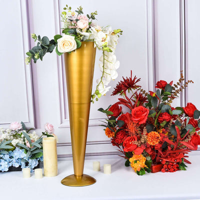 Gold vase with flowers and greenery in a decorative arrangement.