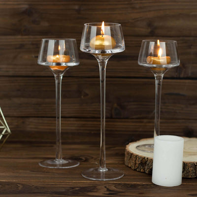 Elegant glass candle holders with floating candles on a rustic wooden table.