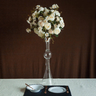 Elegant floral centerpiece in a glass vase with dinnerware set below.