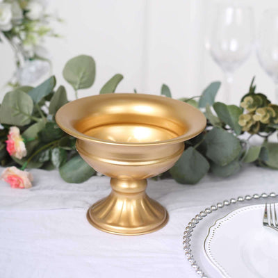 Gold decorative bowl on a table with greenery and floral accents.