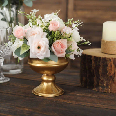 Gold vase with pink and white flowers on a rustic wooden table.