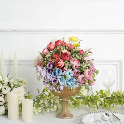 Colorful floral centerpiece in a gold vase with candles and greenery.