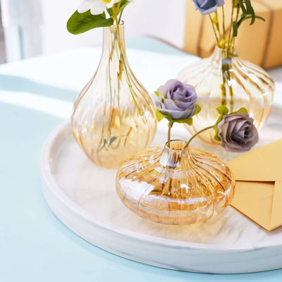 Decorative glass vases with flowers on a marble tray.