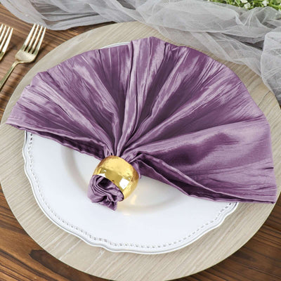 Purple satin napkin elegantly folded on a white plate with a gold napkin ring.