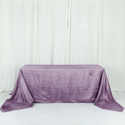 Purple tablecloth draped over a table against a white backdrop.