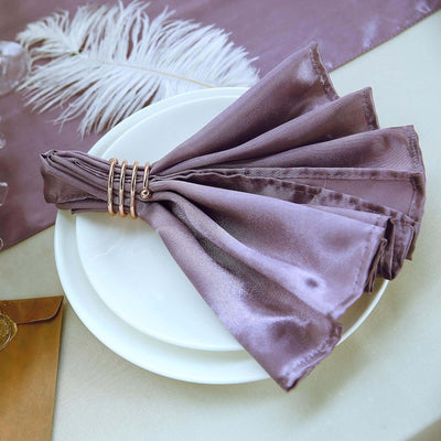 Elegant mauve satin napkins styled on a white plate with a decorative napkin ring.