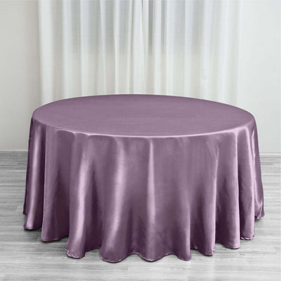 Round lavender satin tablecloth on a wooden floor.