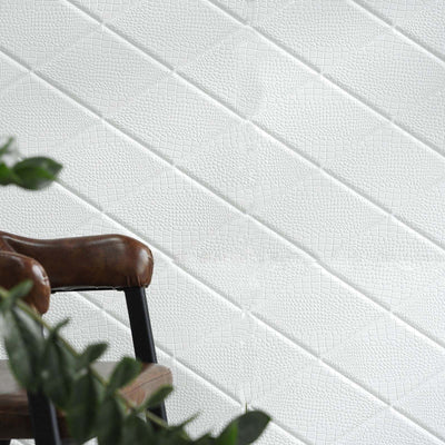 Textured white wall with a subtle pattern, featuring a cozy chair in the foreground.