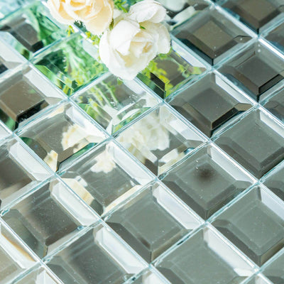 Decorative mirrored tiles with floral accents on a reflective surface.