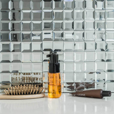 Hair care products on a reflective surface with styling tools.